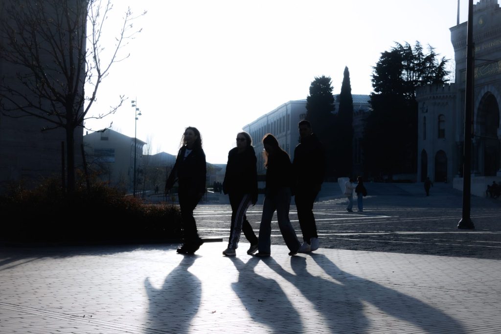 Silhouettes of four people walking in the early morning light on a street in Istanbul, Türkiye.