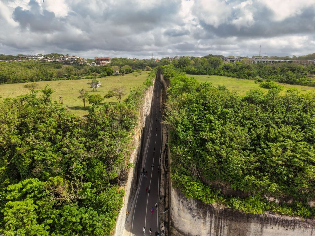 Aerial shot of a road cutting through lush green cliffs in Bali.